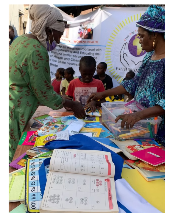 Women and children sorting books and learning materials at a F.A.I.T.H. education activity