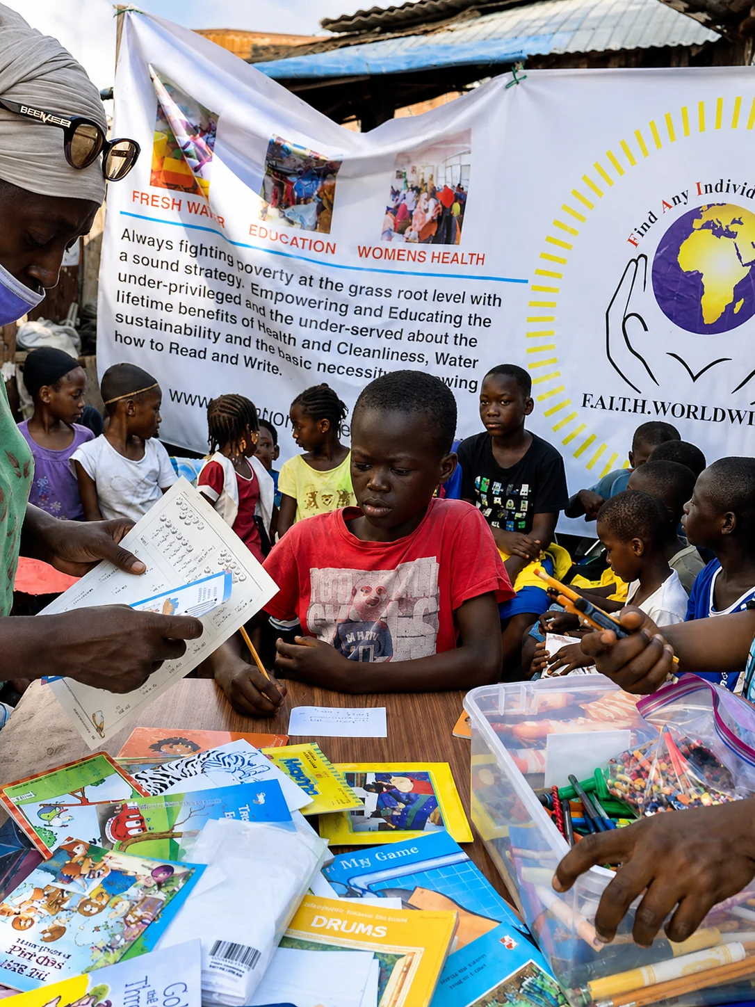 Children using books and learning supplies at a F.A.I.T.H. Worldwide community education activity