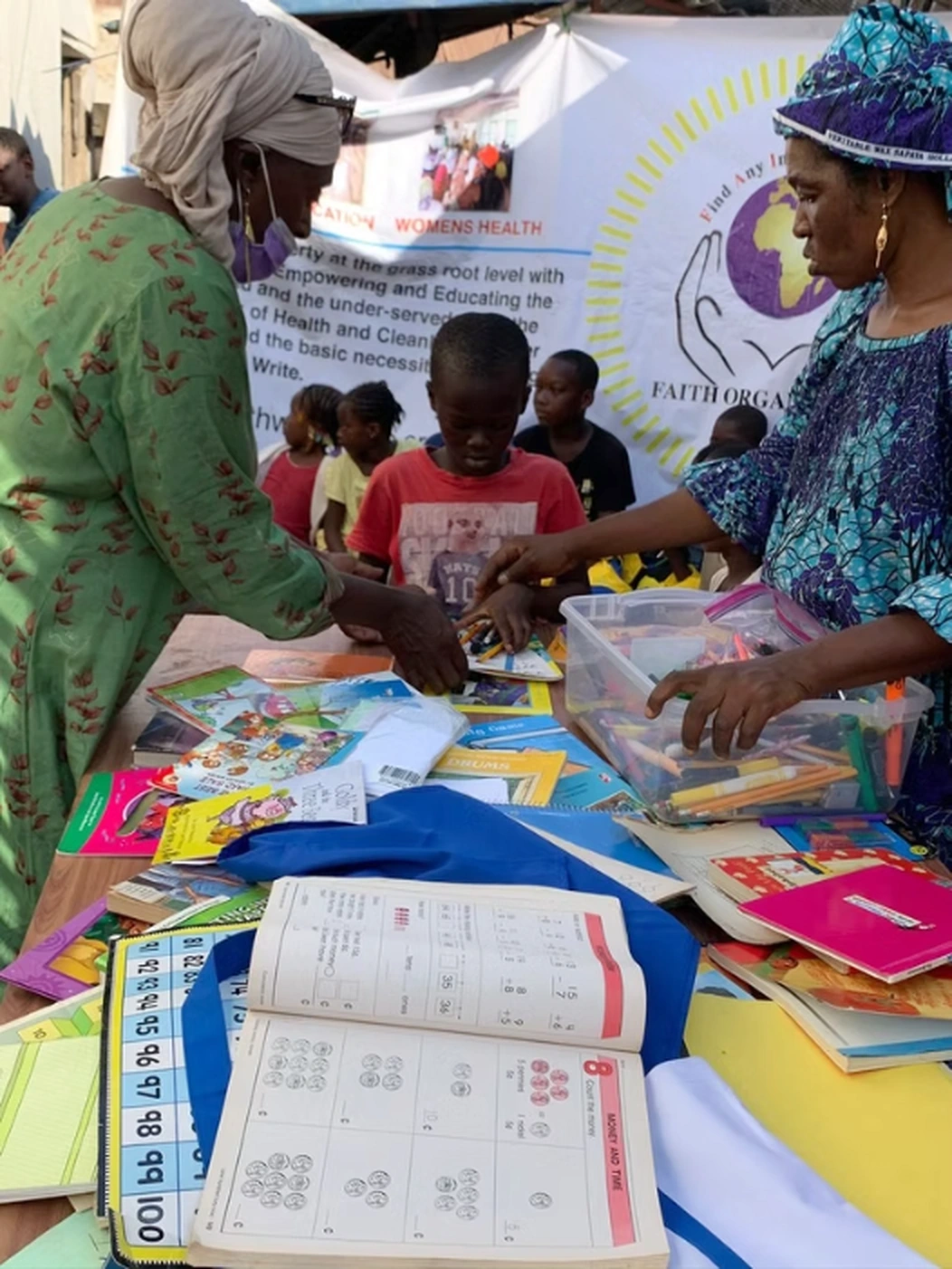 Children and adults sharing books and learning supplies at a F.A.I.T.H. community activity